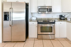 Una cocina con electrodomésticos de acero inoxidable, incluyendo un refrigerador, microondas y horno.