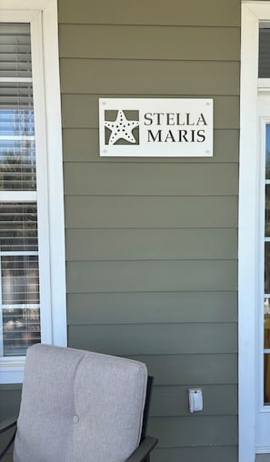 Une enseigne fixée au mur, ornée d’une étoile et du nom « STELLA MARIS », sur un fond de bardage extérieur vert.