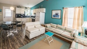 Un espace de vie compact comprenant un coin cuisine, un coin repas et un espace détente avec un canapé et une petite table.