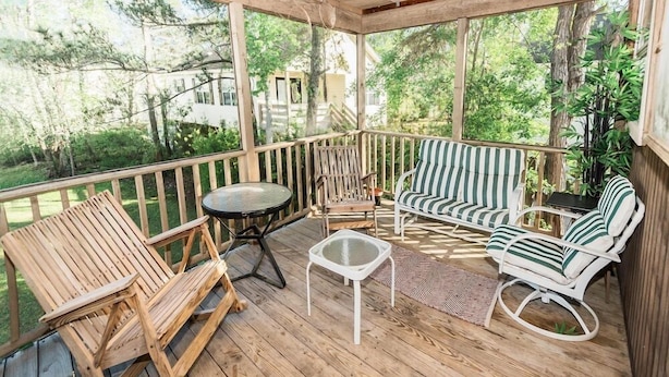 Une terrasse en bois avec une chaise berçante, un canapé à rayures et une petite table.