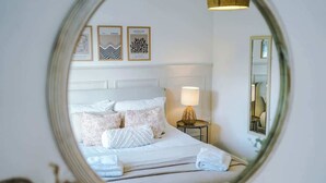 Een hotelkamer met een bed, een bedlamp en lijstjes met kunst aan de muur.