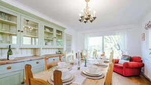 Een eetkamer met een houten tafel gedekt voor vier personen, omringd door lichtgroene kasten en een rode bank.