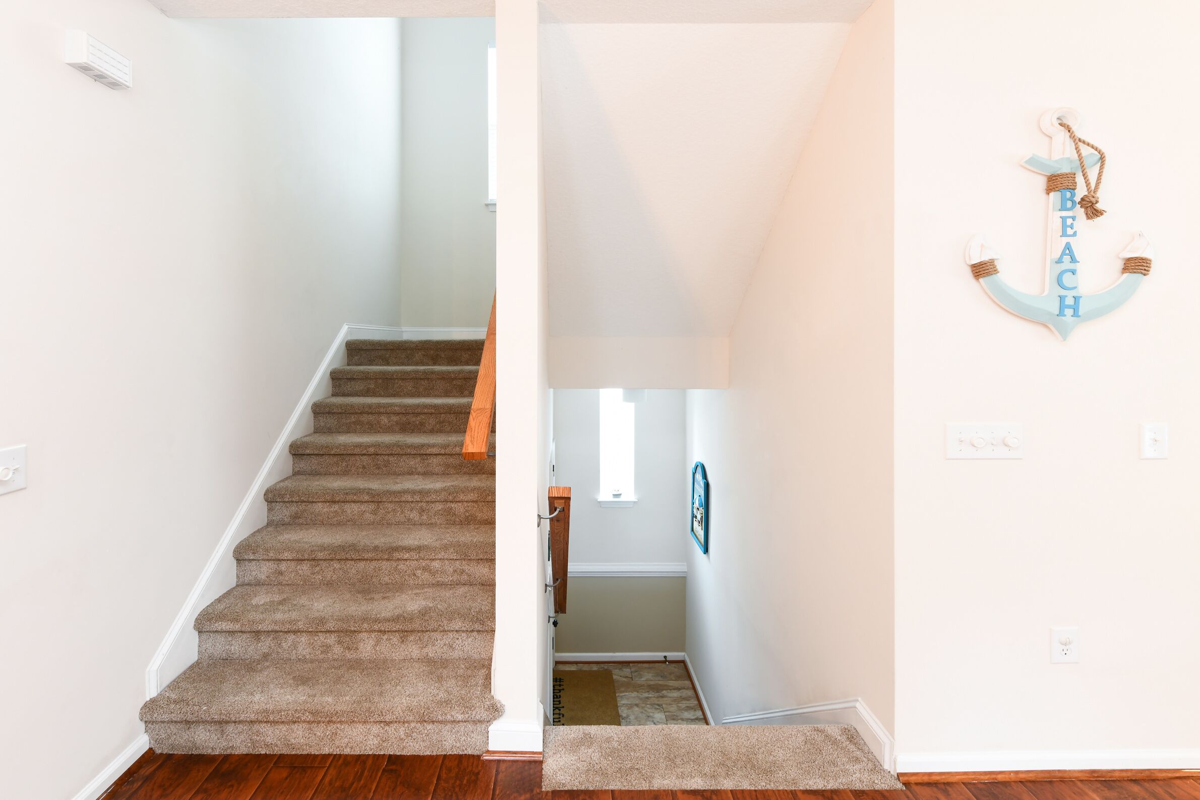 A staircase leading to a landing with a wooden handrail and carpeted steps.
