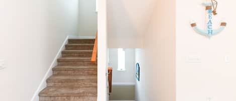 A staircase leading to a landing with a wooden handrail and carpeted steps.
