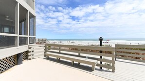 Een promenade aan het strand met een houten bankje, uitzicht op de zee en een strand op de achtergrond.