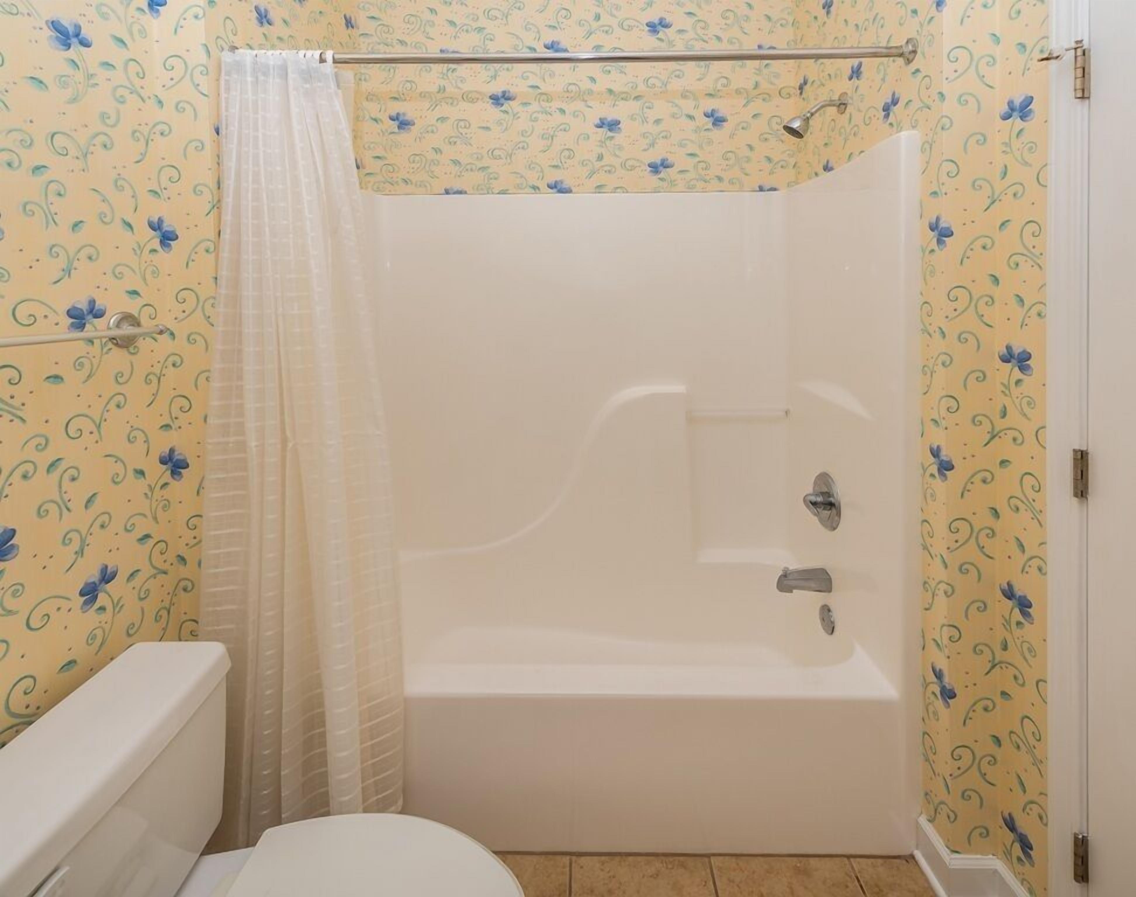 Un baño con bañera, inodoro y cortina de ducha.
