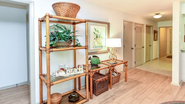 Une étagère en bambou ornée de plantes et d’une lampe, un panier en osier et un autre panier en osier contenant un saladier.