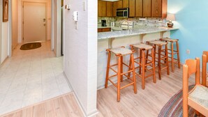 Une cuisine moderne avec des meubles en bois, un four à micro-ondes et un coin bar équipé de tabourets.