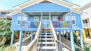 Ein Strandhaus mit Balkon und Treppe zum Eingang.