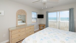 Ein Schlafzimmer mit einem großen Bett, einem Schminktisch, einem Fernseher und einem Balkon mit Meerblick.