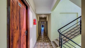 A hallway with a wooden door labeled "U-02", a fire extinguisher, and a staircase with a metal railing. - Urban Drift by Urban Hotels (Bengaluru)