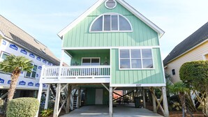 Ein zweistöckiges Haus mit Balkon, Garage und kleiner Veranda.