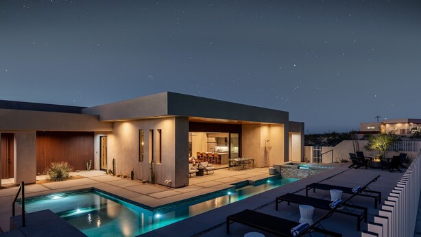 Ein modernes Haus mit Schwimmbad, Sitzgelegenheiten im Freien und einer Terrassenfläche.