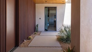 Ein modernes Gebäude mit Holzboden, einem Betonweg und Kakteen an den Seiten.