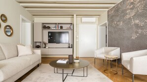 A modern living room with a sofa, armchairs, a coffee table, and a TV.