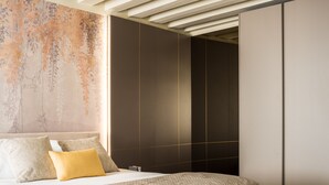 A modern bedroom with a large bed, a decorative wall, and a wardrobe.