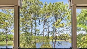 A view through a window with a view of a lake, trees, and a golf course.
