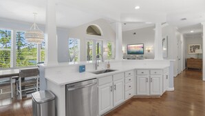 A modern kitchen with white cabinetry, a stainless steel dishwasher, and a large island.
