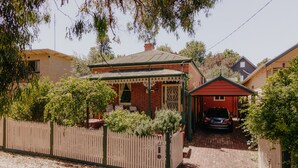 A residential property with a brick house, a red garage, and a fenced yard.