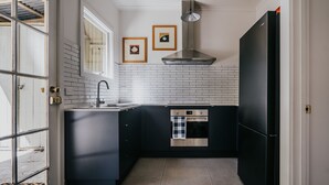 A modern kitchen with dark cabinetry, a stainless steel oven, and a black refrigerator.
