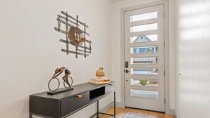 A modern entryway with a black console table, a decorative metal wall piece, and a door with multiple glass panels. - Fairway Getaway #55 3 Bedroom Townhouse (Santa Clara)