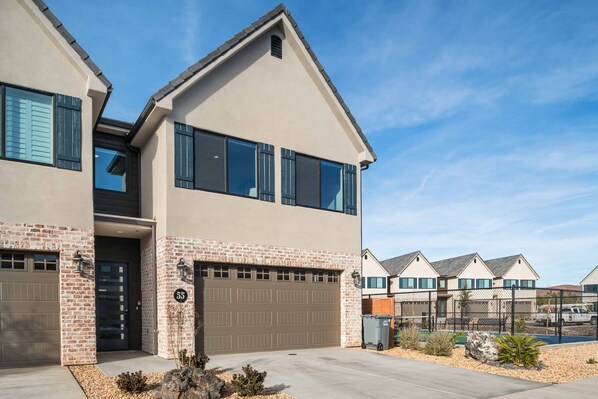 A modern two-story house with a garage, brick facade, and large windows.