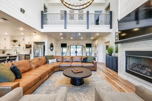 A spacious living area with a large sectional sofa, a round coffee table, and a fireplace. - Luxe Group Getaway w/ 2-story Deck in Broken Bow! (Broken Bow)