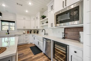 A modern kitchen with white cabinetry, stainless steel appliances, and a wooden floor. - Luxe Group Getaway w/ 2-story Deck in Broken Bow! (Broken Bow)