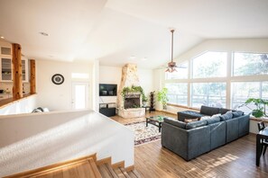 A spacious living area with a fireplace, a large sofa, and a dining table. - Private Luxury Getaway Fire Pit Near Weddings (Dripping Springs)
