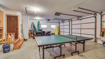A garage with a ping pong table, a door, and a motorcycle.