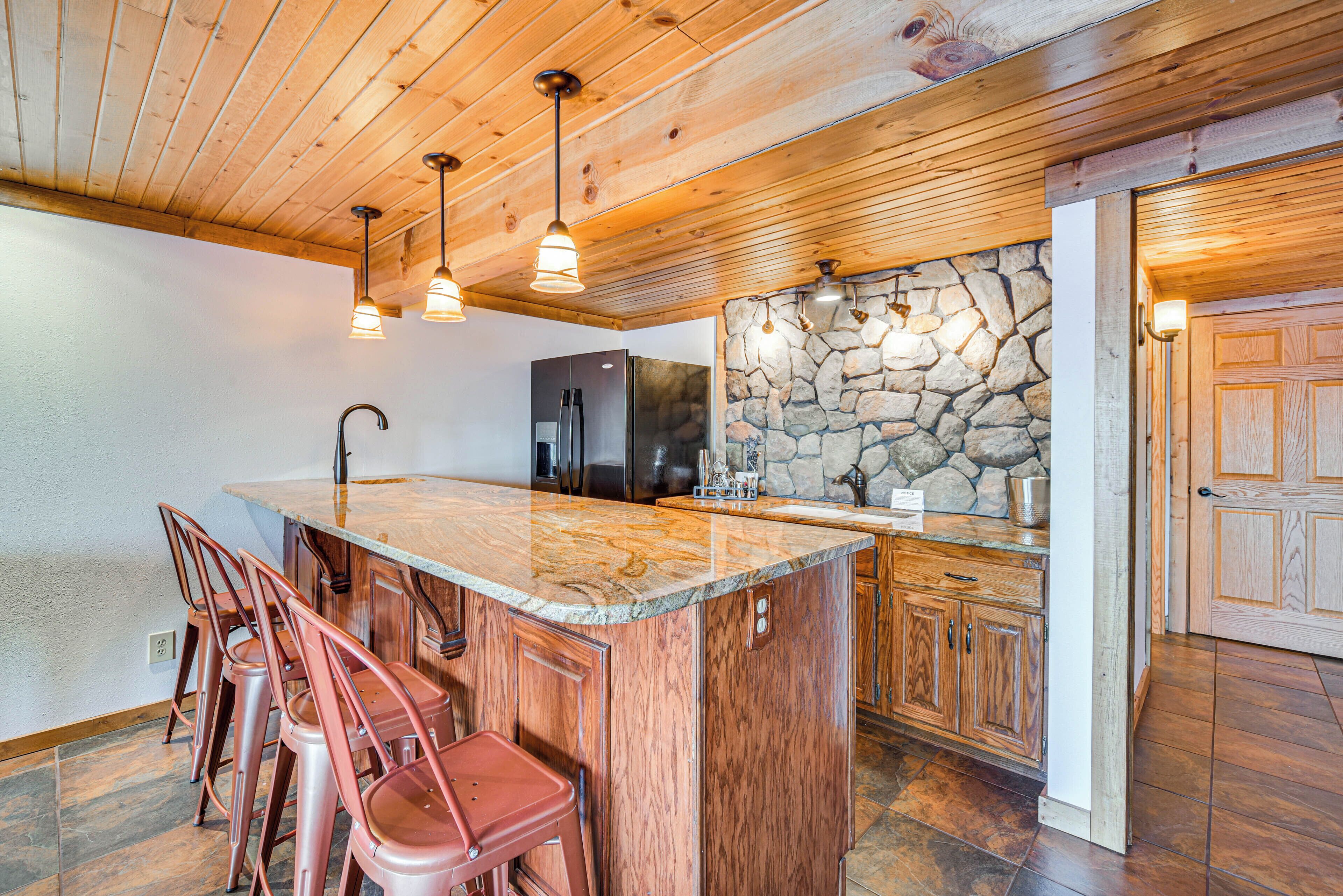 Une cuisine avec un plafond en bois, un mur en pierre et un grand îlot central doté de tabourets de bar.