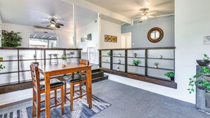 A dining area with a wooden table and chairs, a grey carpet, and a bookshelf with plants. - Fort Walton Home w/ Shared Pool - 2 Mi to Beach! (Fort Walton Beach)