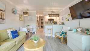 Un salon moderne avec un canapé, une table basse, un coin repas et une cuisine en arrière-plan.