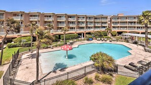 Un hôtel doté d’une piscine, de palmiers et d’une fontaine rouge en forme de champignon.