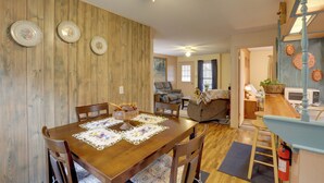 Un coin repas avec une table en bois, des chaises et un ventilateur de plafond. Il y a également un coin cuisine équipé d’un four à micro-ondes et d’un évier.