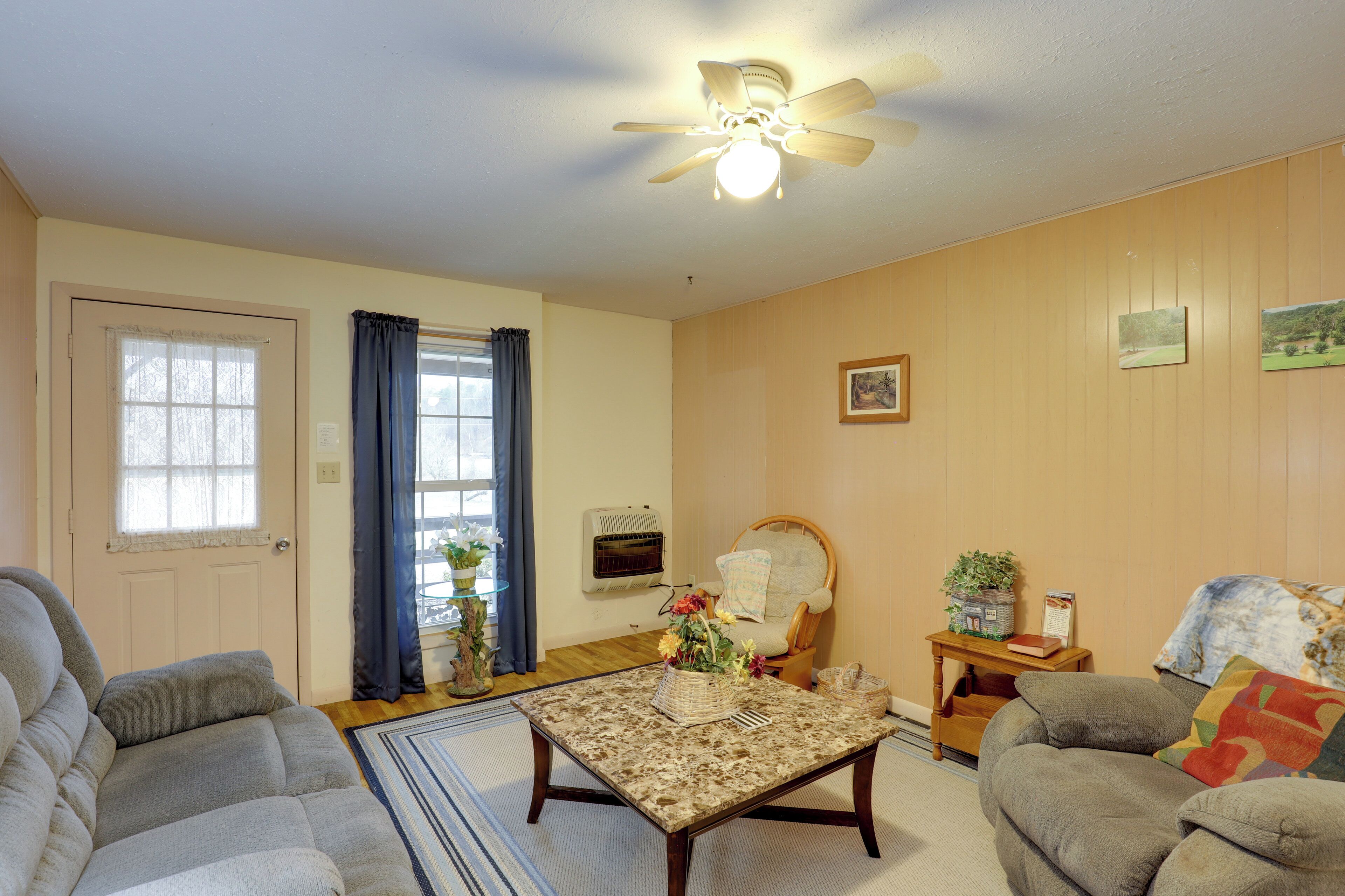 A living room with a ceiling fan, a sofa, a coffee table, and a chair.