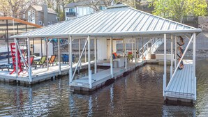 A covered dock with seating and a small staircase leading to a house. - Private Dock! Waterfront Sunrise Beach Rental (Sunrise Beach)