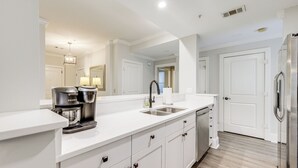A modern kitchen with white cabinetry, a stainless steel refrigerator, and a built-in coffee maker. - Chic Greensboro Condo w/ Lake Oconee Access! (Greensboro)