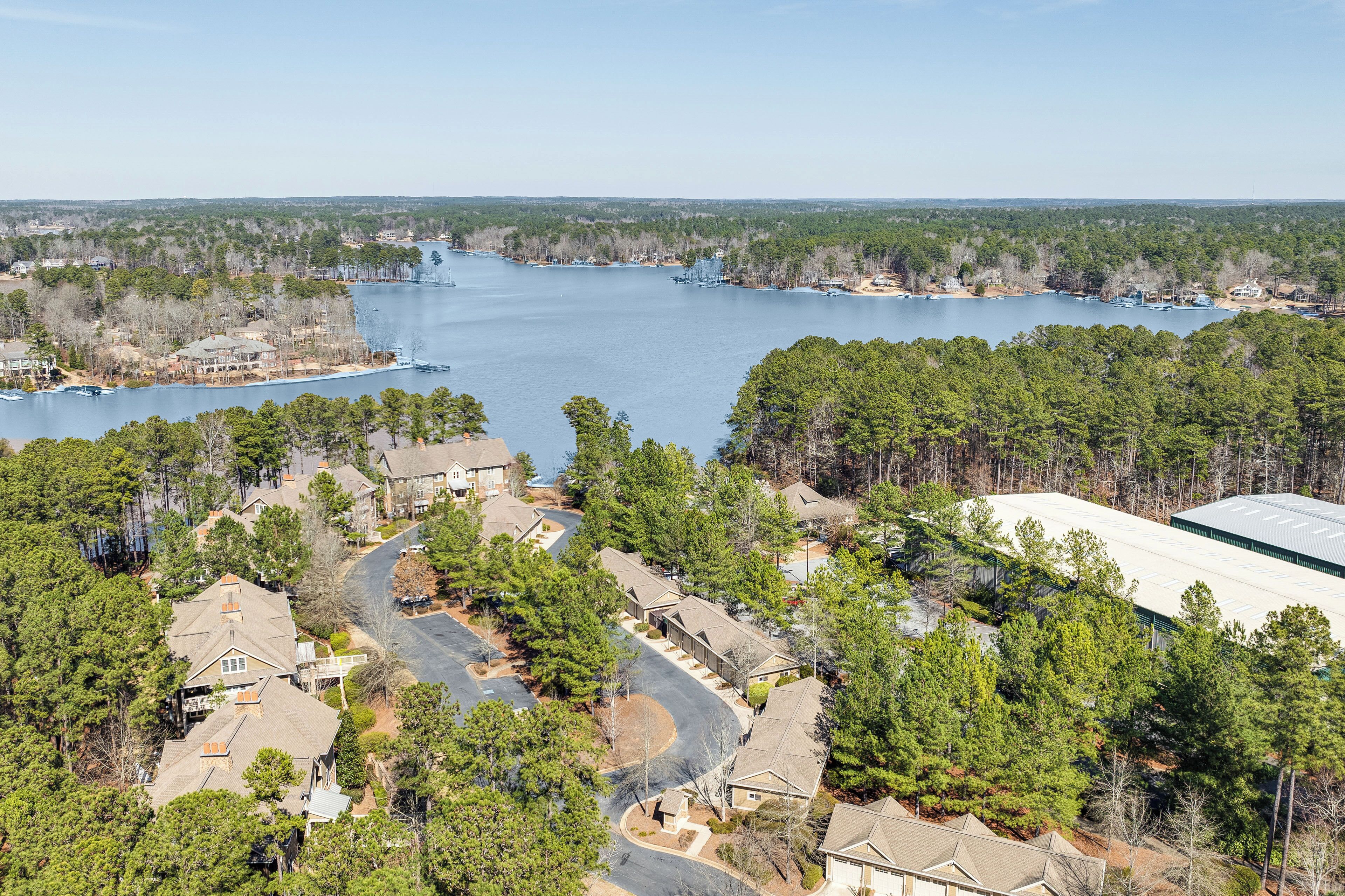 A residential area with houses, a large body of water, and a building with a flat roof.