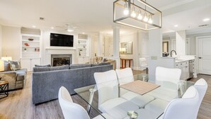 A modern living room with a glass dining table, grey sofas, and a fireplace. - Chic Greensboro Condo w/ Lake Oconee Access! (Greensboro)