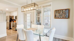 A modern kitchen with white cabinetry, stainless steel appliances, and a glass dining table with white chairs. - Chic Greensboro Condo w/ Lake Oconee Access! (Greensboro)