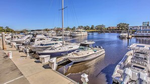 A marina with multiple boats docked, a clear sky, and a calm water surface. - Swim, Golf & Unwind: Barefoot Resort Condo (North Myrtle Beach)