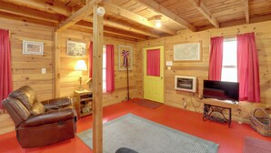 L’intérieur chaleureux d’un chalet avec un fauteuil inclinable en cuir, un téléviseur et un plafond en bois.