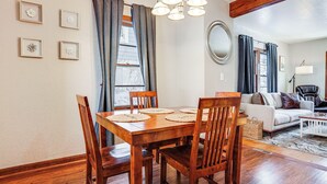 Zona pranzo con tavolo e sedie in legno, un'opera d'arte floreale appesa alla parete e vista sul soggiorno.