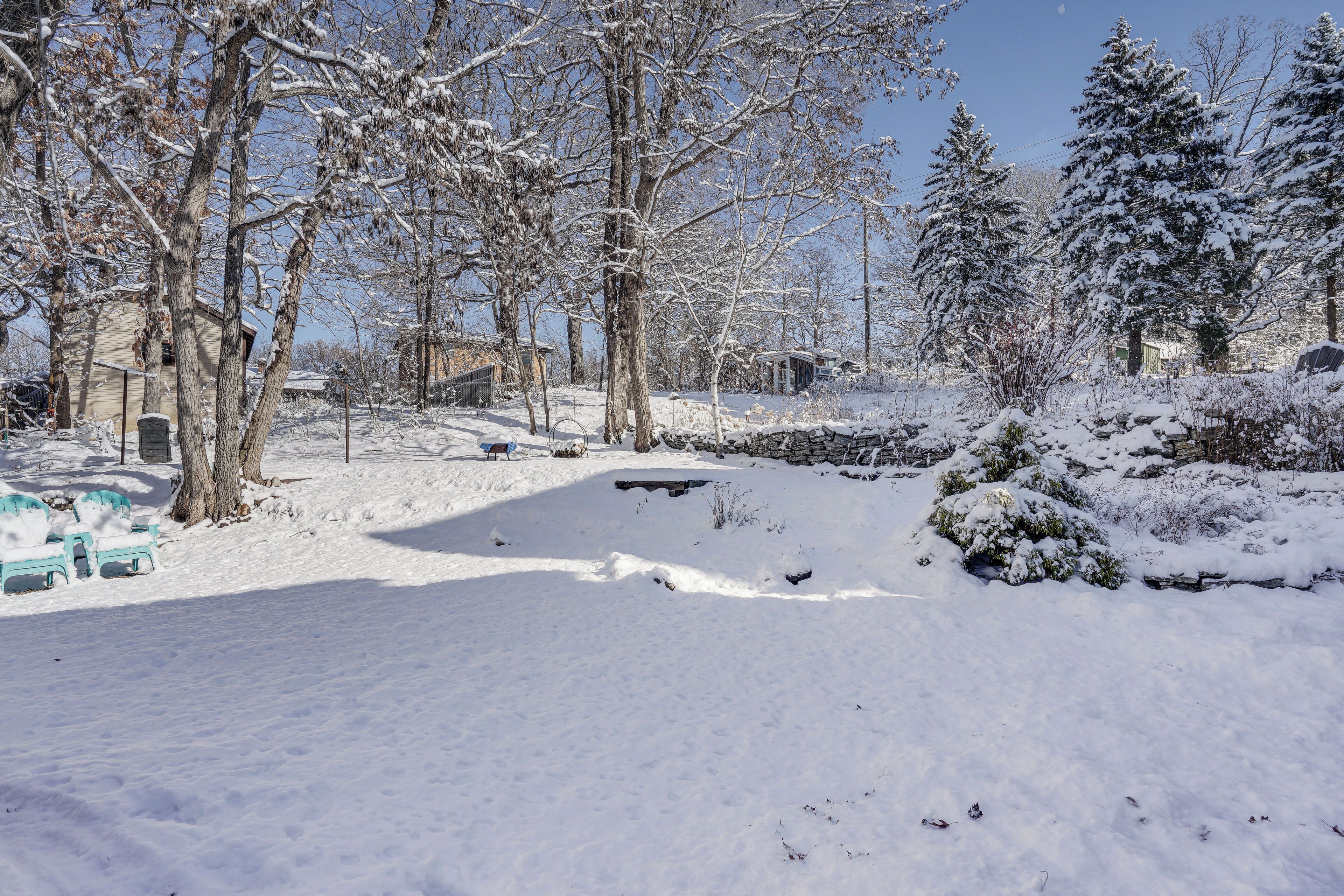A snowy landscape with trees and a small building.