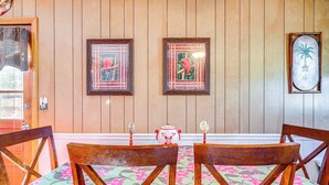 Ein Zimmer mit Holzwänden, einem Esstisch, Stühlen und gerahmten Kunstwerken an der Wand.