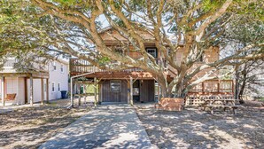 Ein zweistöckiges Holzhaus mit einer Veranda und einem großen Baum davor.
