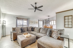 A spacious living room with a sectional sofa, a ceiling fan, and a dining area with a table and chairs. - Spacious Holiday Island Escape w/ Deck & Gas Grill (Eureka Springs)