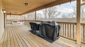 A covered deck with a wooden floor, a table with chairs, and barbecue grills. - Spacious Holiday Island Escape w/ Deck & Gas Grill (Eureka Springs)