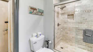 A bathroom with a toilet, a shower with a glass door, and a towel hanging on the wall. - Spacious Holiday Island Escape w/ Deck & Gas Grill (Eureka Springs)